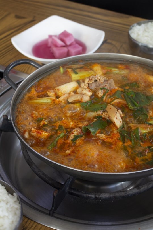 버너 위에서 보글보글 끓는 와촌돼지찌개와 공기밥, 무절임